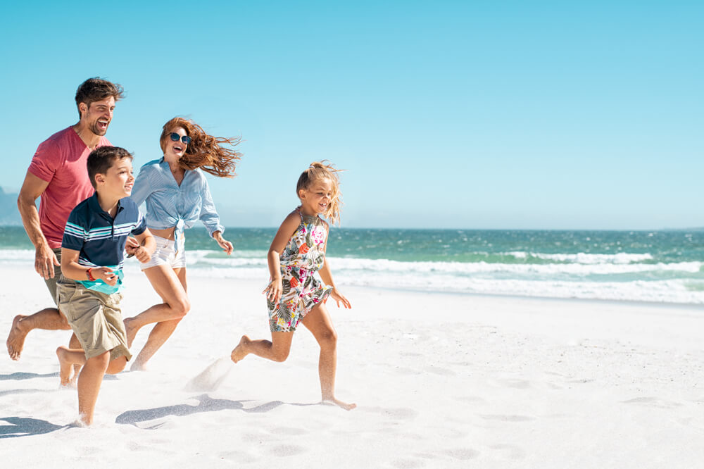 A family running on the beach during their North Carolina summer getaway.